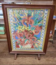 A polychrome embroidered tapestry firescreen, in wooden mount.