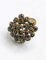 A yellow metal and sapphire domed cluster ring, the round-cut sapphires within slender rope-twist