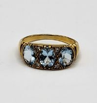 A yellow metal, diamond, and aquamarine ring, set with three mixed oval-cut aquamarines,