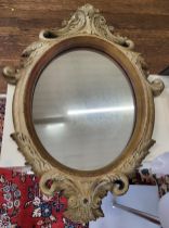 An ornate round wall mirror with painted frame. 84cm x 62cm