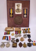 A large quantity of military medals and ribbons including a mounted sepia image of a soldier in