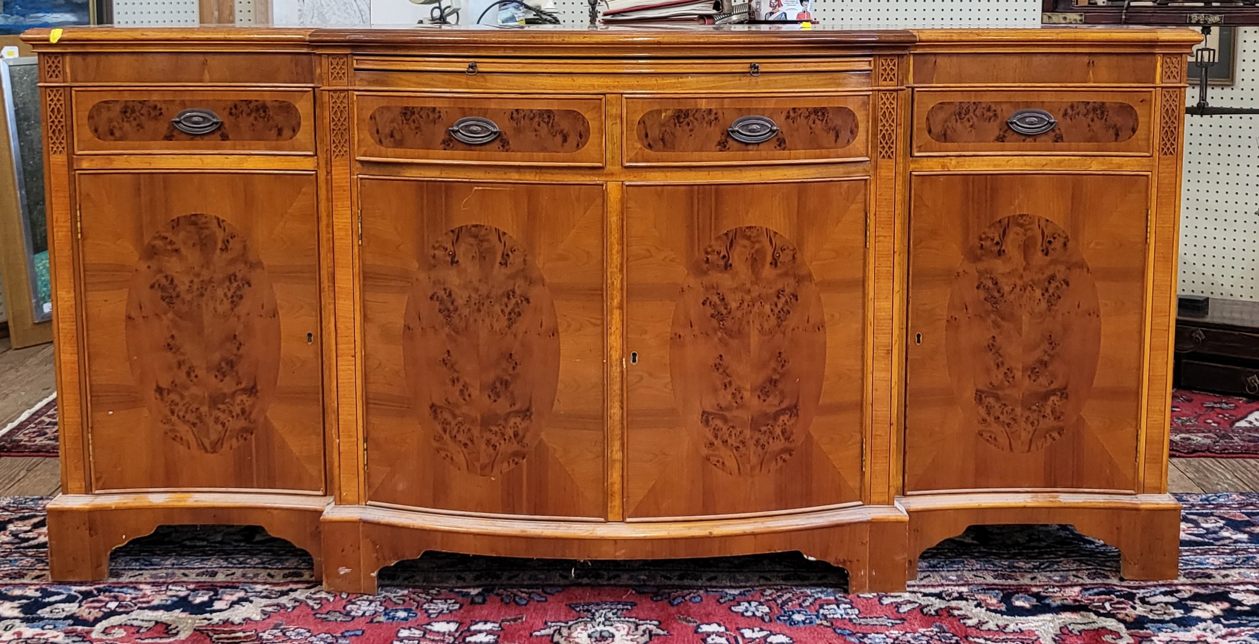 A modern veneered burred yew sideboard, the shaped frontage with four drawers and four cupboard