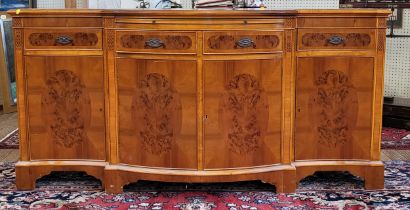 A modern veneered burred yew sideboard, the shaped frontage with four drawers and four cupboard