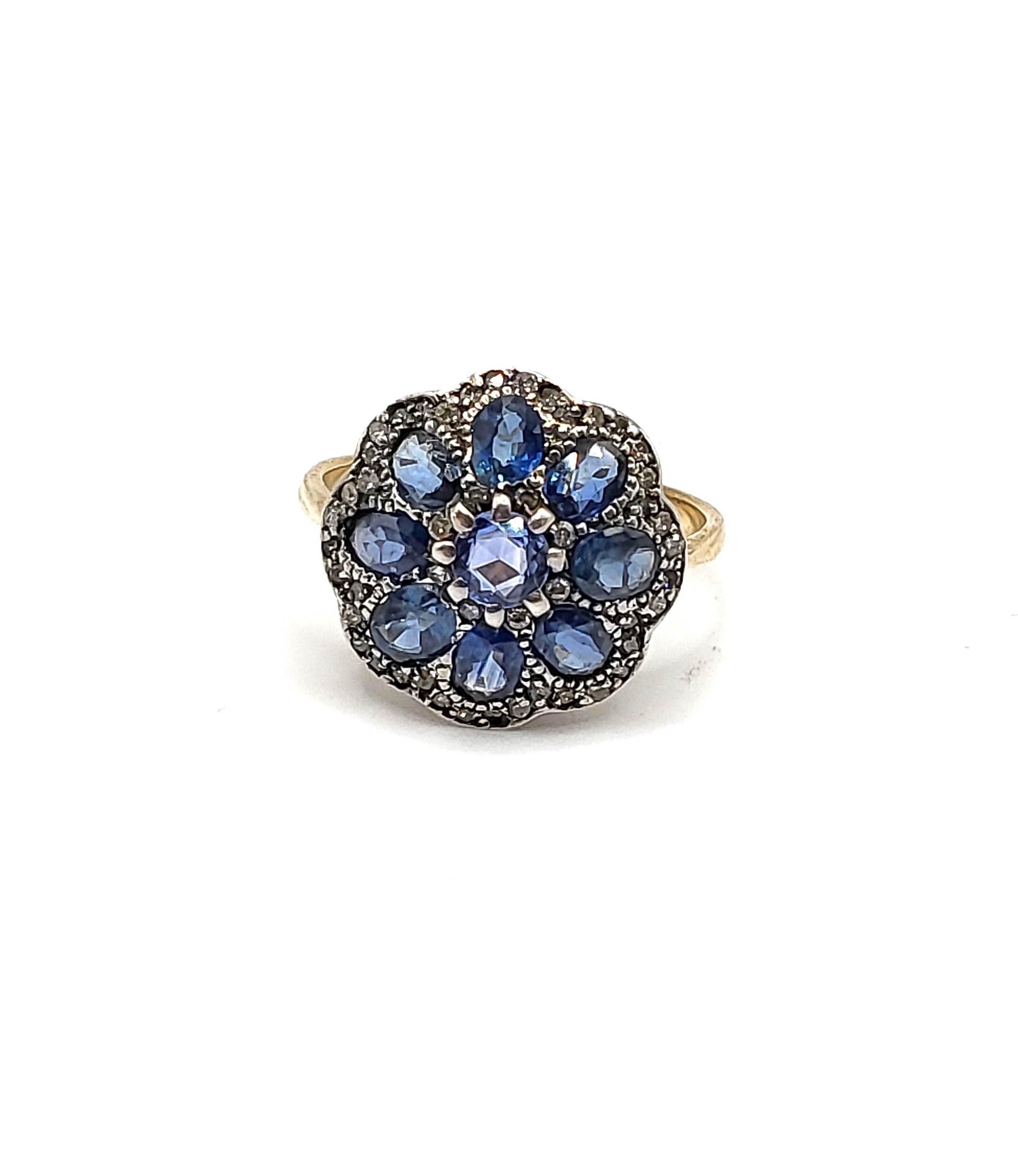 A yellow metal, sapphire, and diamond daisy cluster ring, the silver mount inset with mixed oval and