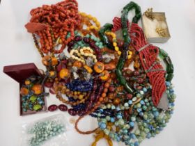 A group of costume jewellery, including various beaded necklaces, amber style necklaces, coral-style