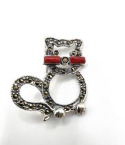 A silver and marcasite cat brooch with red whiskers, and marcasite detail.