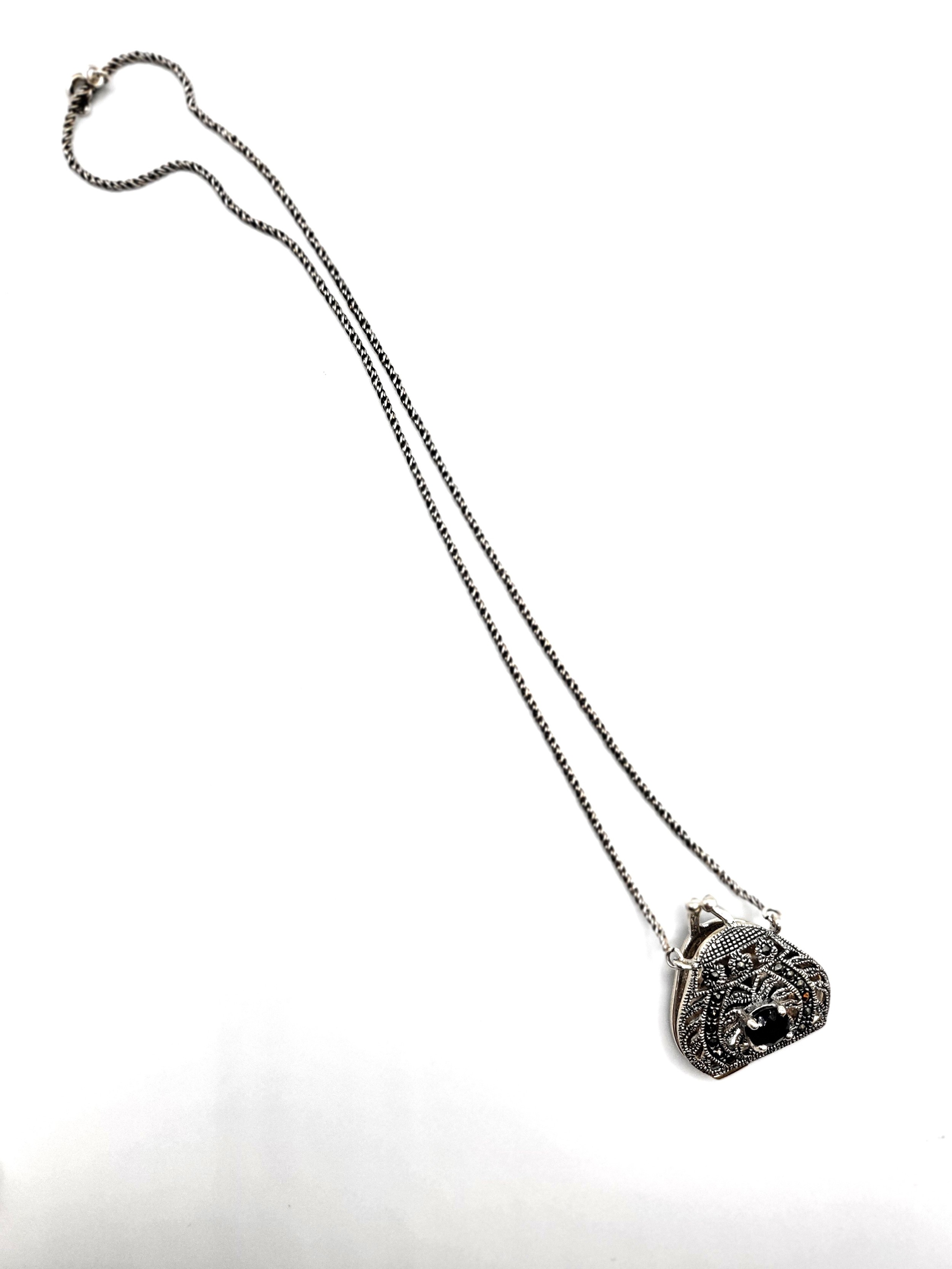 A silver photo locket pendant in the form of a purse, suspended on a silver chain.