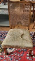 A rattan-backed low bedroom chair, with fabric upholstered seat, on shaped legs.