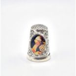 A silver thimble, set with a small oval plaque depicting a lady sewing. 2.5cm