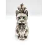 A novelty pin cushion in the form of a seated cat with green eyes, wearing a crown, with red