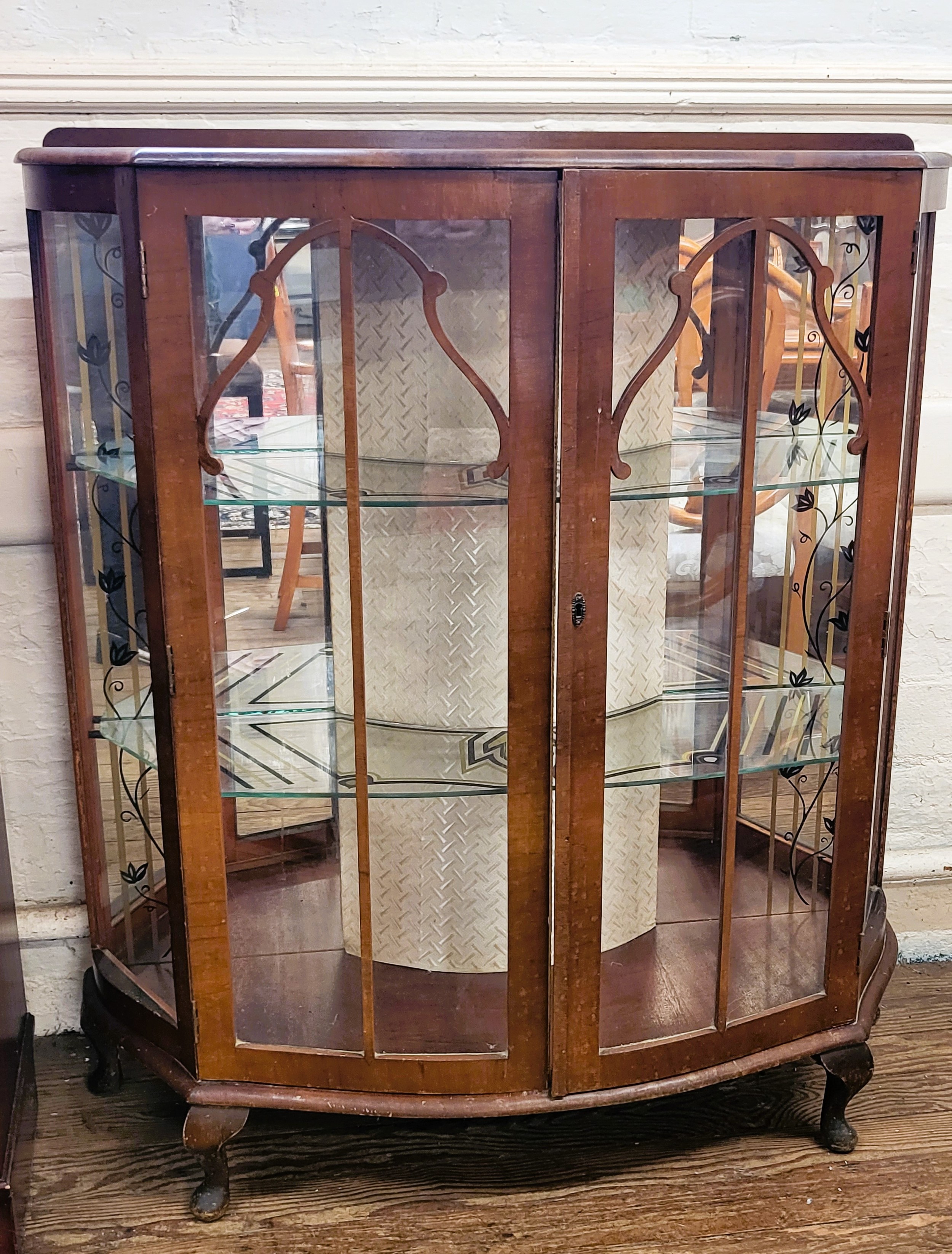 Art Deco bow front glass display cabinet with black and gold decoration to the two glass shelves.