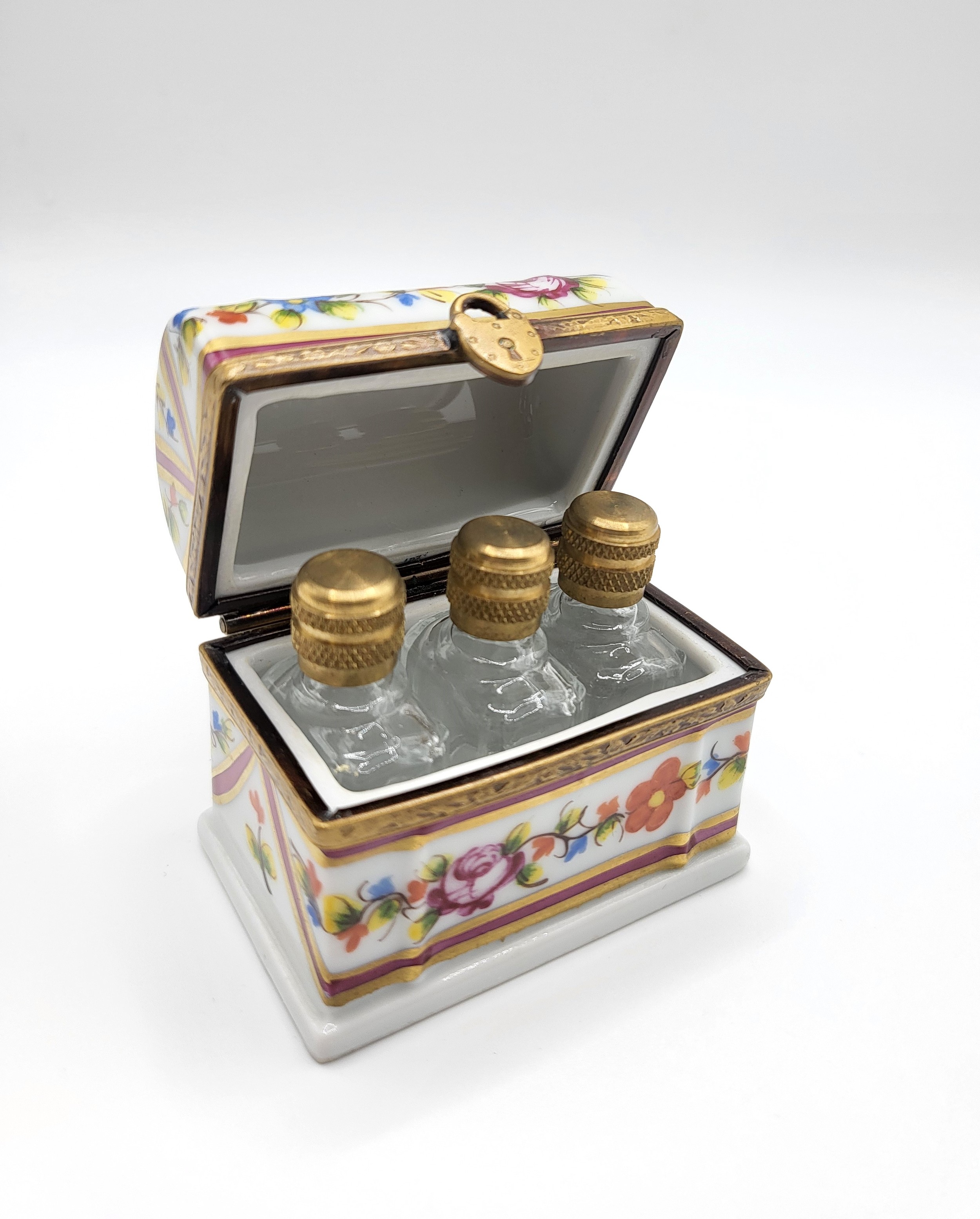 A hand-painted Limoge box, with polychrome decoration, containing three miniature perfume