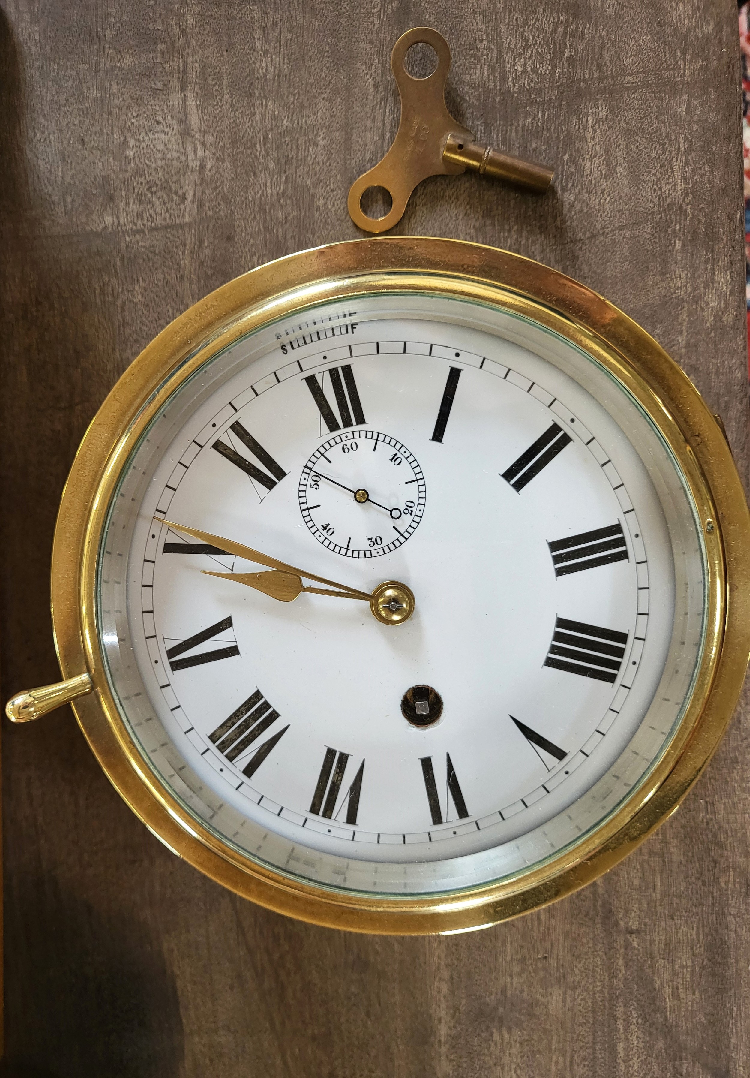 A Victorian brass ship's clock with key. 17cm diameter.