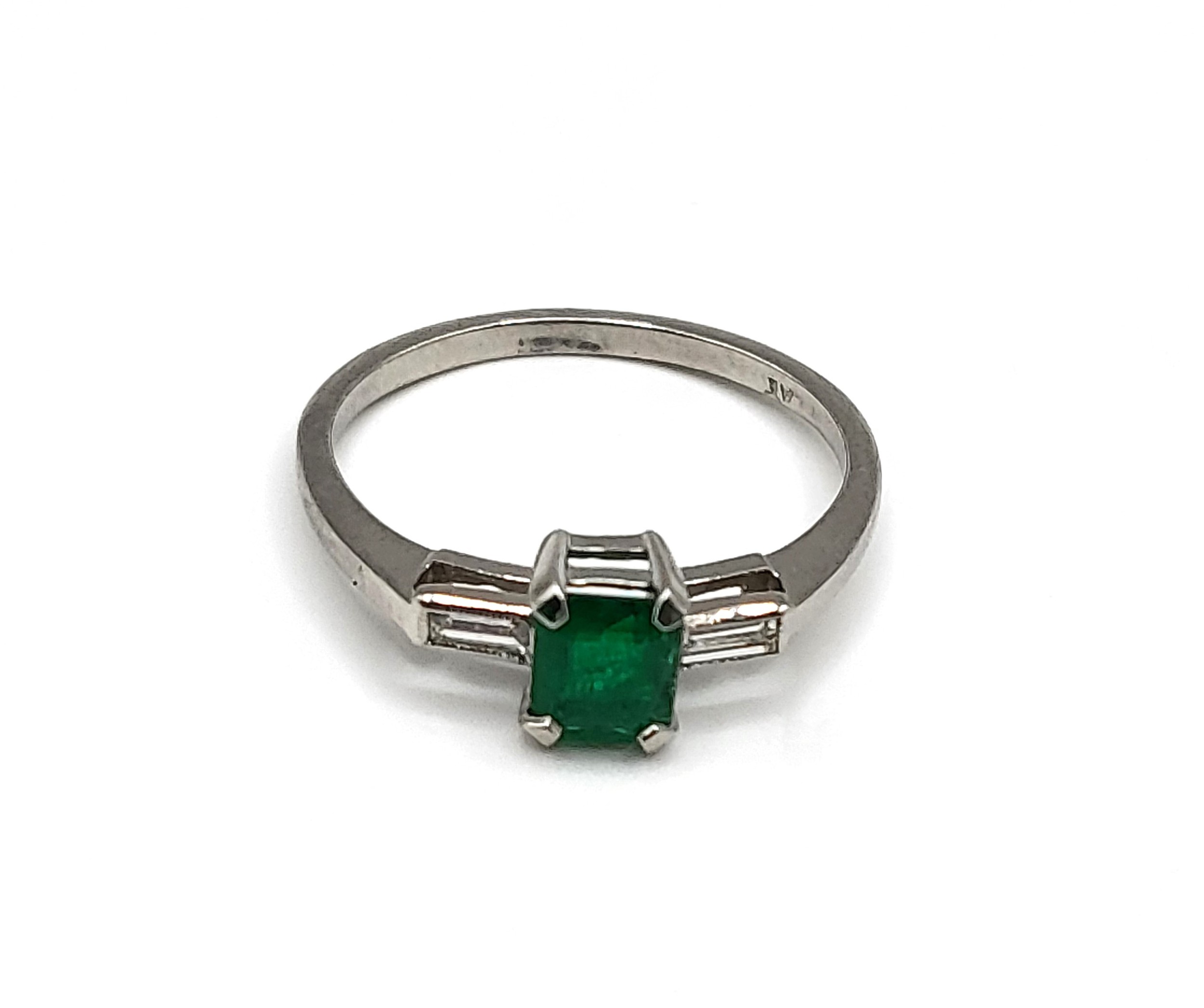 A platinum, emerald, and diamond ring, centred with a mixed rectangular-cut emerald, of