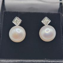 A pair of 18ct white gold, diamond, and pearl earrings, each with a round-cut diamond within a
