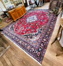 A large red and blue ground rug with central medallion design, multi-bordered and fringed.