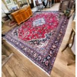 A large red and blue ground rug with central medallion design, multi-bordered and fringed.