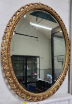 An oval wall mirror with gilt carved wood frame. 70cm x 55cm.