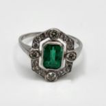 An Art Deco style platinum, emerald, and diamond ring, set with a mixed emerald-cut emerald of