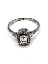 An 18ct white gold and diamond ring, set with an emerald-cut diamond surrounded with round