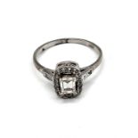 An 18ct white gold and diamond ring, set with an emerald-cut diamond surrounded with round