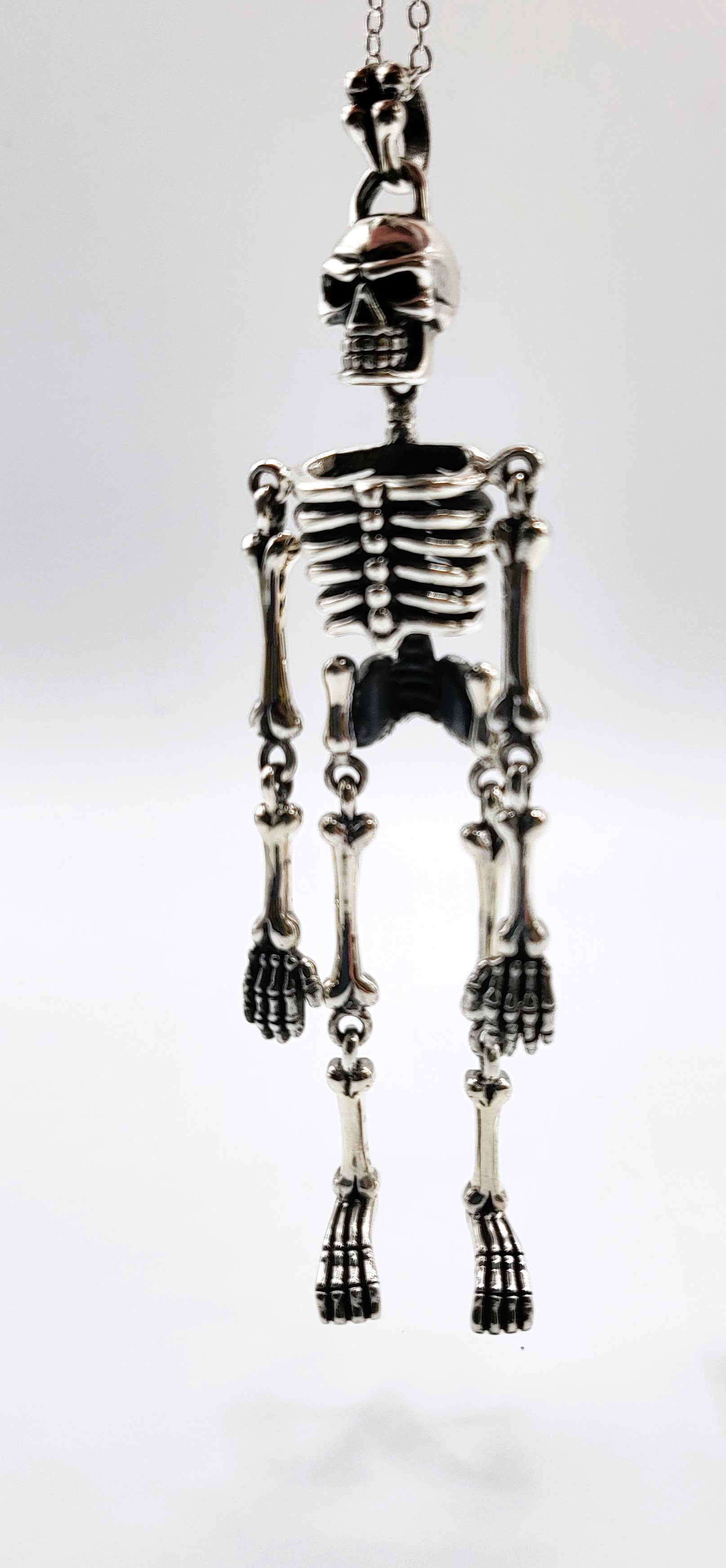 An unusual articulated silver skeleton pendant necklace, suspended on a silver chain. Pendant 8.5cm. - Image 2 of 2