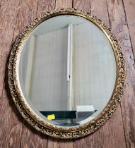 An oval gilt-framed wall mirror measuring 67cm x 47cm.