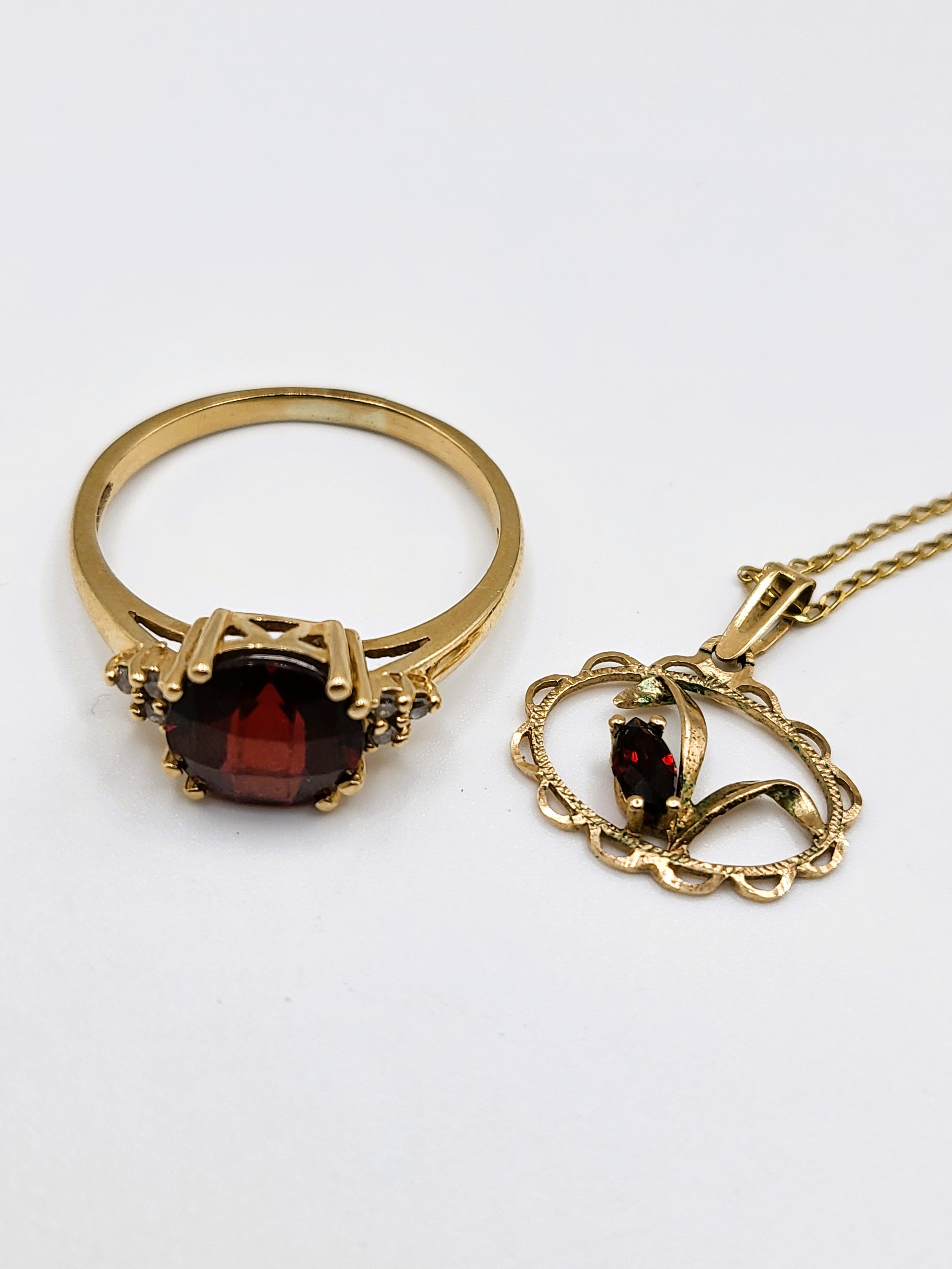 A 9ct yellow gold, diamond, and garnet ring, set with a round chequerboard-cut garnet, size P 1/2,