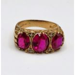 A 9ct yellow gold and red stone ring, set with three mixed oval-cut red stones, interspersed with
