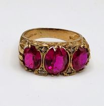 A 9ct yellow gold and red stone ring, set with three mixed oval-cut red stones, interspersed with