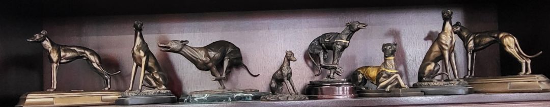 A group of eight spelter greyhounds, in various poses.