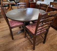 A circular dining table and four ladder-bark dining chairs with red upholstery. Table measures