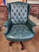 A green leather swivel office chair, with green leather buttoned upholstery, supported on pedestal