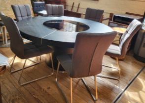 An unusual large black circular table with a tempered glass lazy susan insert, on a circular