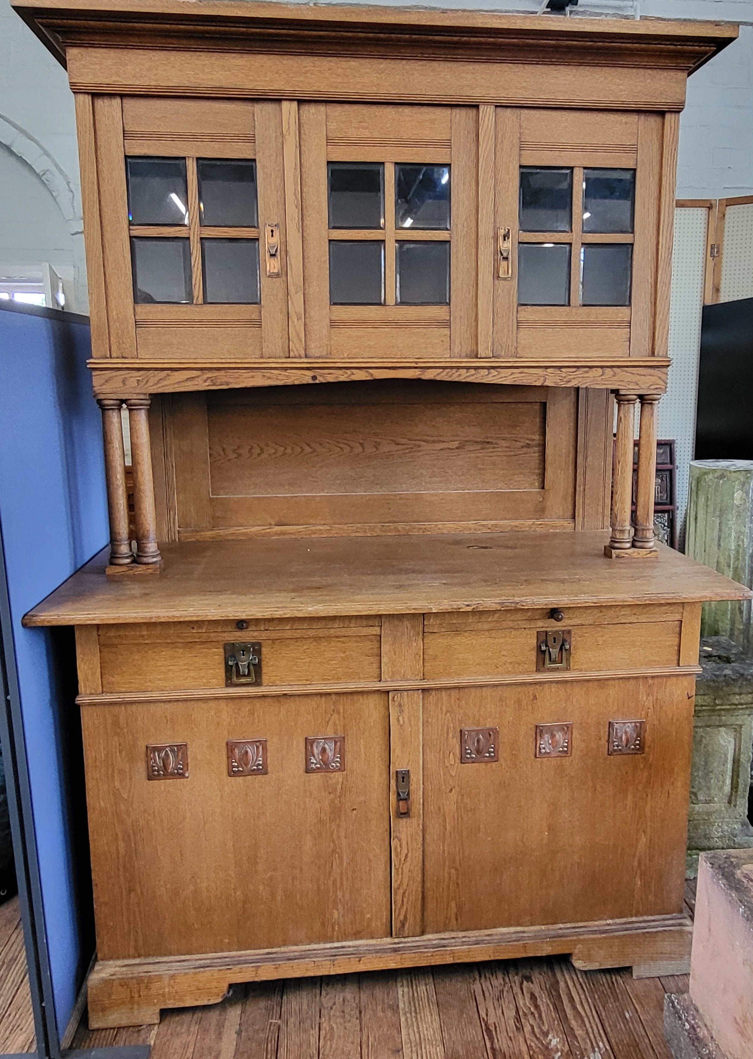A large Arts and Crafts oak dresser, having glazed cupboards over turned column supports, dresser