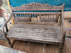 An ornately carved wooden garden bench. 98cm x 120cm x 52cm