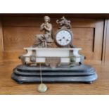 An ornate mantle clock, the white dial beside the seated figure of a Classical woman, raised on