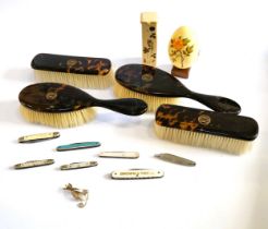 A tin containing seven penknives, and four tortoiseshell brushes, and a gold coloured hatpin/ brooch