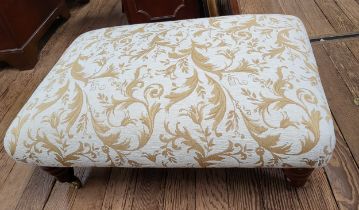 A foot stool on casters upholstered in cream and beige with fauna decoration. 30cm x 84cm x 60cm.