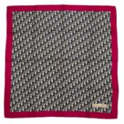 A Christian Dior silk scarf featuring the logo in a repetitive geometric design with a fuchsia