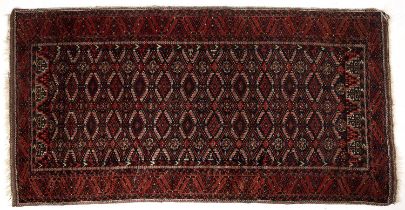An early 20th century Balouch red ground rug with diamond motifs 99cm x 191cm and middle eastern red