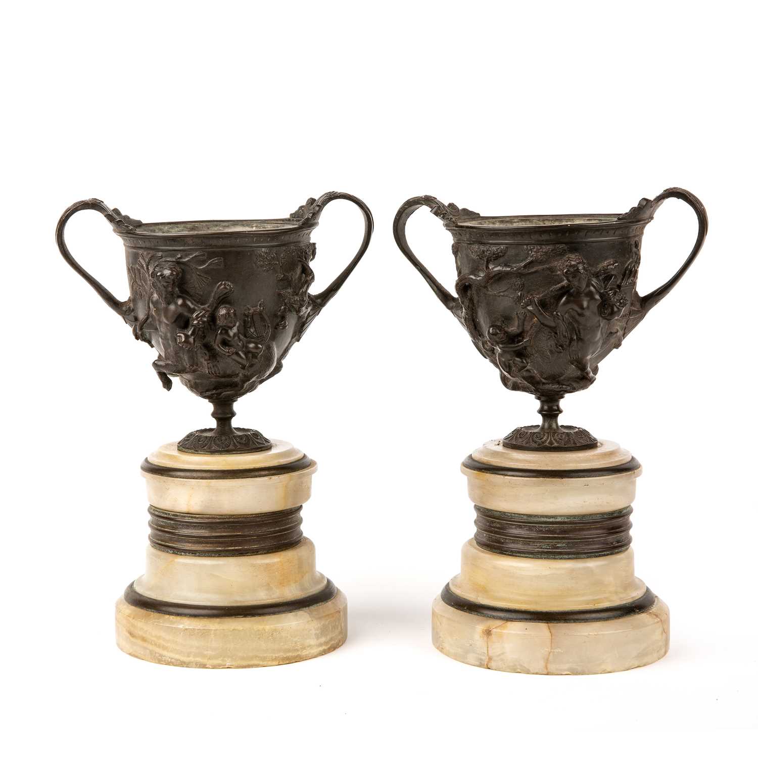 A pair of 19th century Grand Tour bronze urns with Centaurs in relief and mounted on alabaster socle