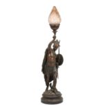 An antique patinated spelter lamp in the form of an American Indian holding a bow, having a frosted
