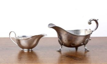 Two silver sauce boats the larger example standing on three feet, with scroll capped handle, bearing