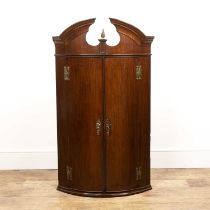 Mahogany bow front corner cupboard George III, with an arched cornice and brass flame finial,