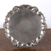 George II silver salver or tray with shell and scrollwork border, standing on three pad feet,