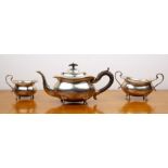 Three piece silver tea set comprising a teapot, twin handled sucrier and milk jug, all standing on