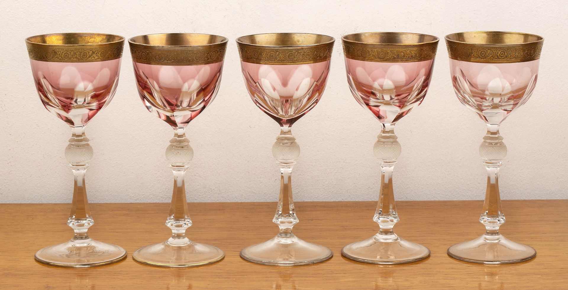 Set of five Bohemian wine glasses with faceted flashed bowl, gilt rim, with etched stem, unmarked,