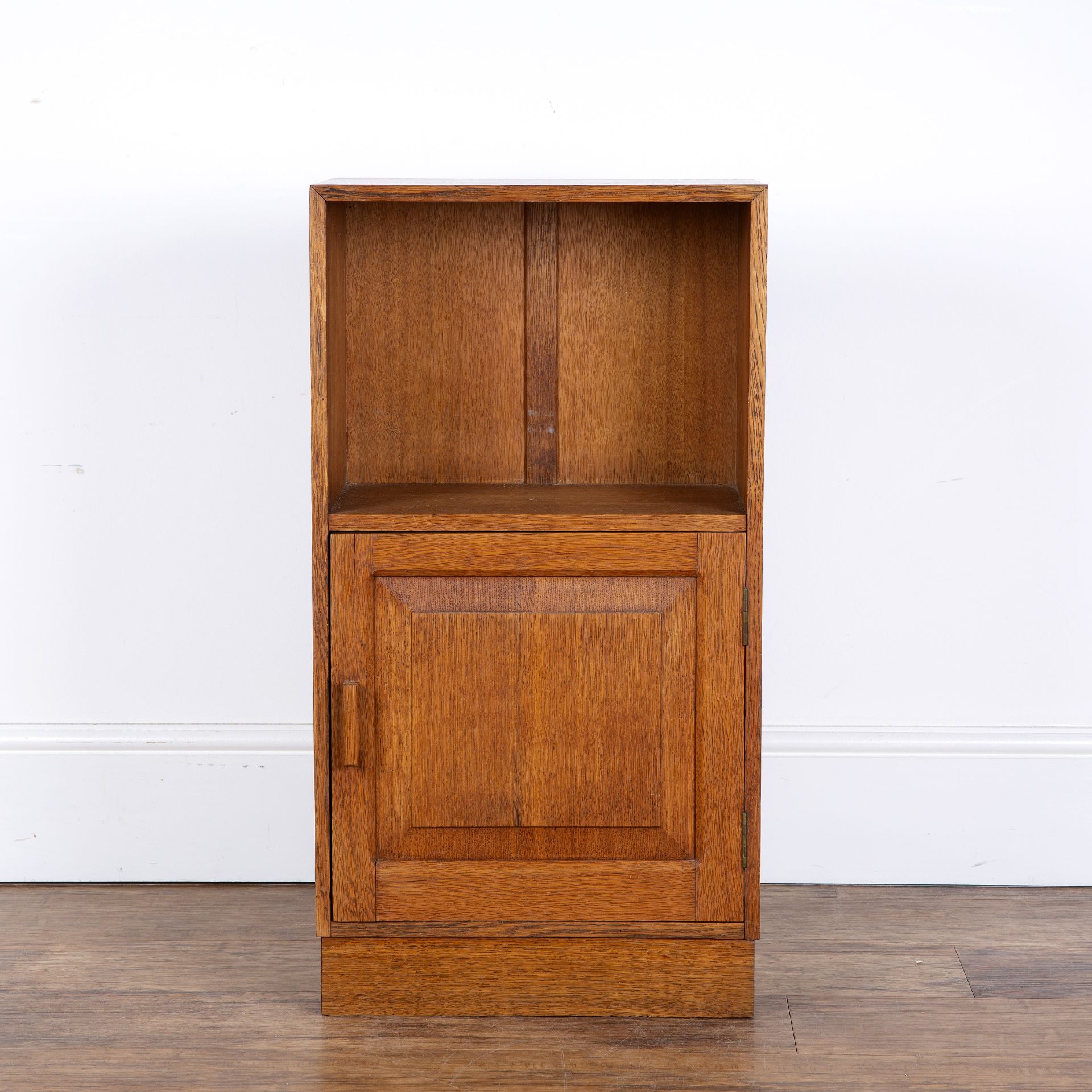 Attributed to Heals oak, small cupboard or bedside table, with open shelf above a fielded panel