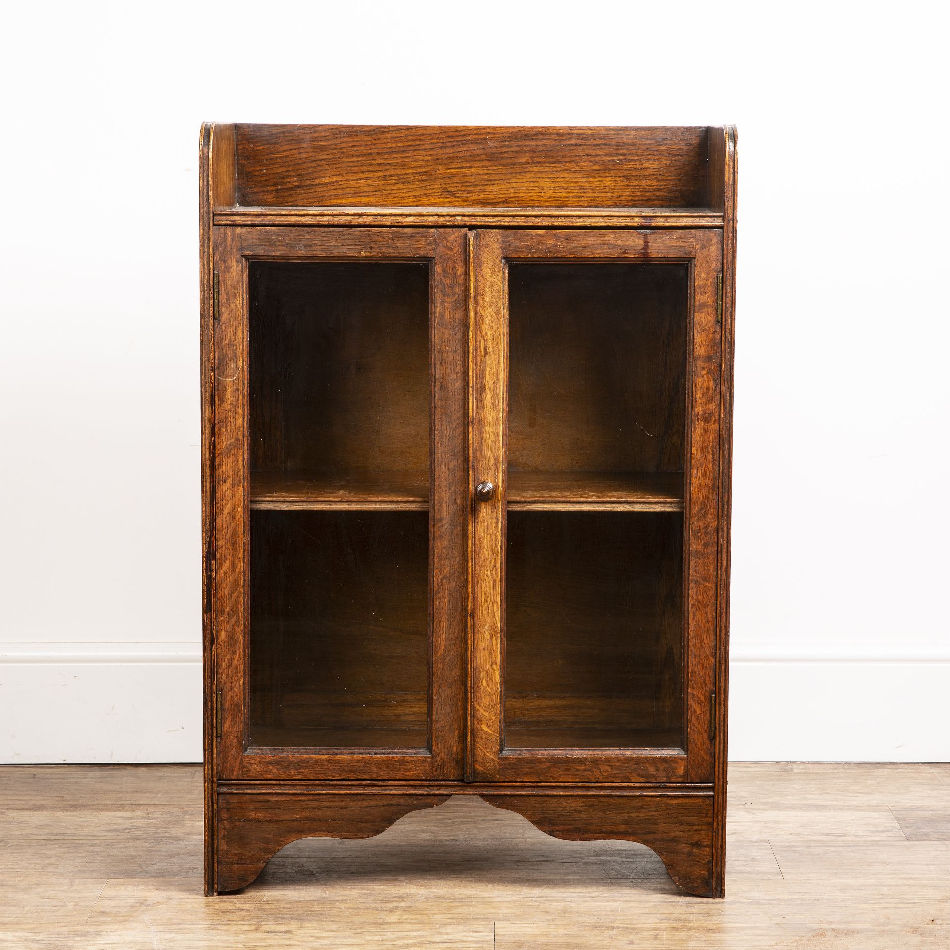 Attributed to Heals oak cupboard, with galleried top, two glazed panel doors with a turned wooden